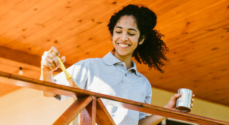 woman painting exterior fence railing